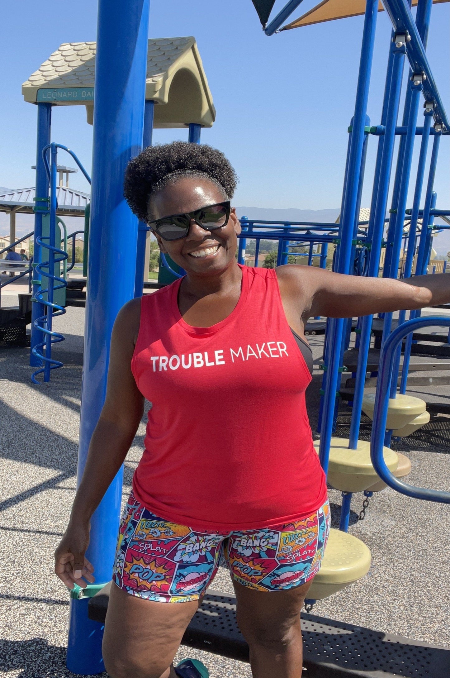 Black woman wearing a red shirt that says Trouble Maker