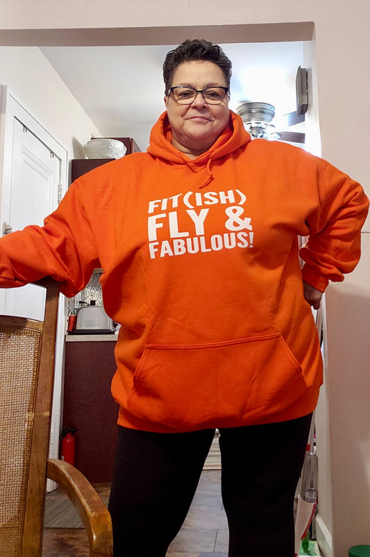 Woman wearing an orange hoodie that says Fit(ish) Fly & Fabulous