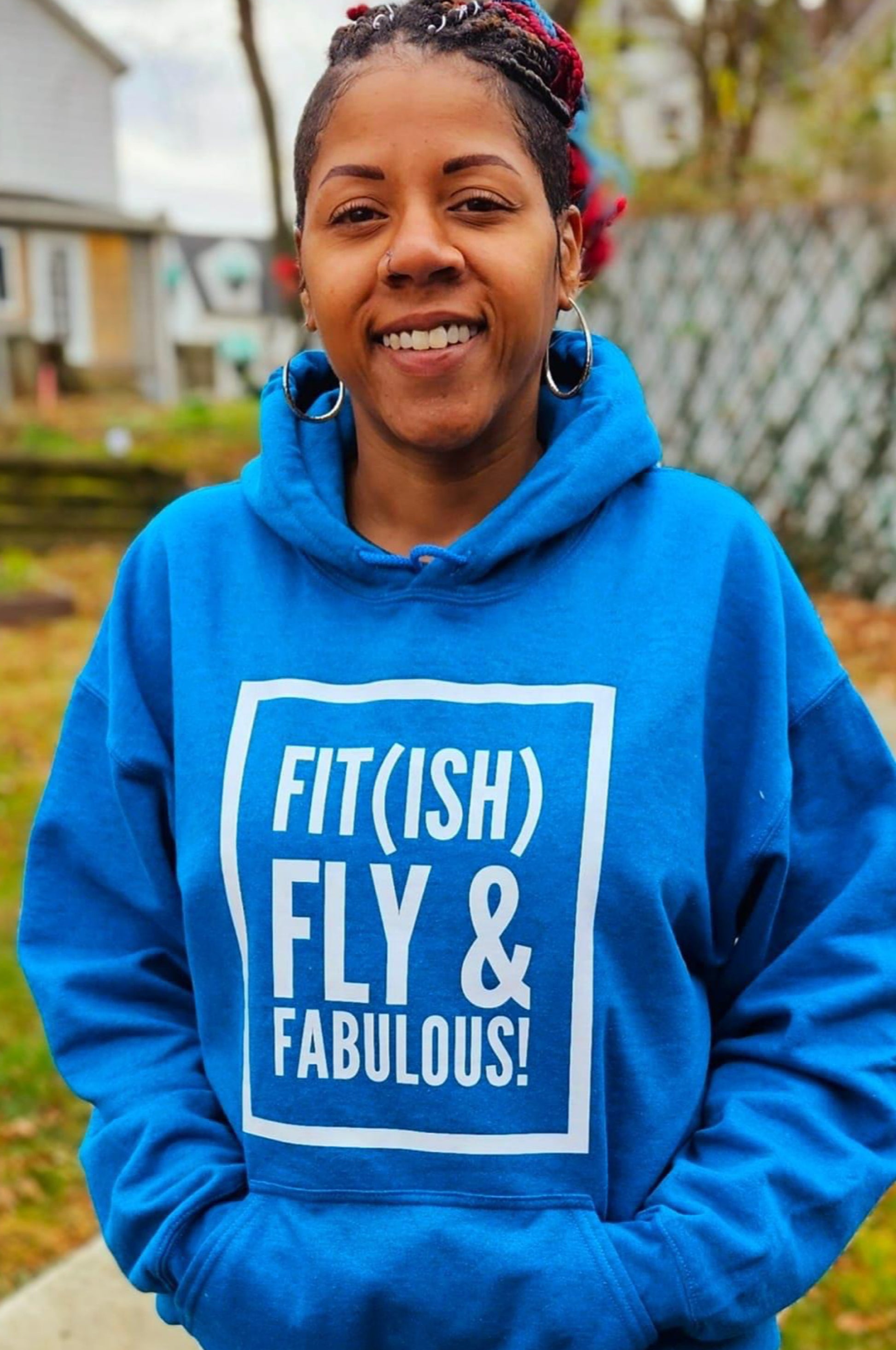 A Black woman with braids wearing a blue hoodie that says Fit(ish) Fly & Fabulous 