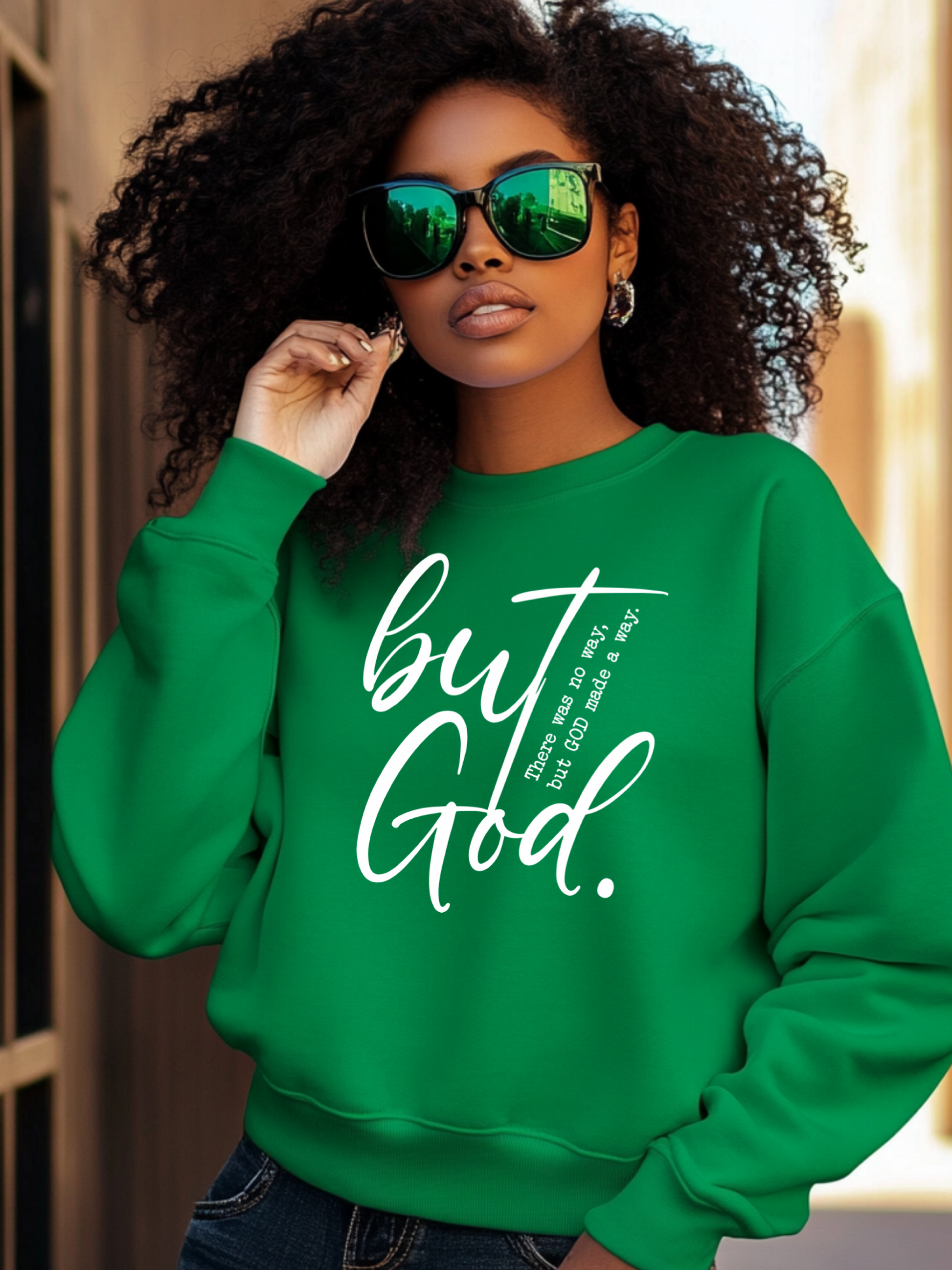 Woman wearing a green sweatshirt with 'but God' text, standing outdoors.