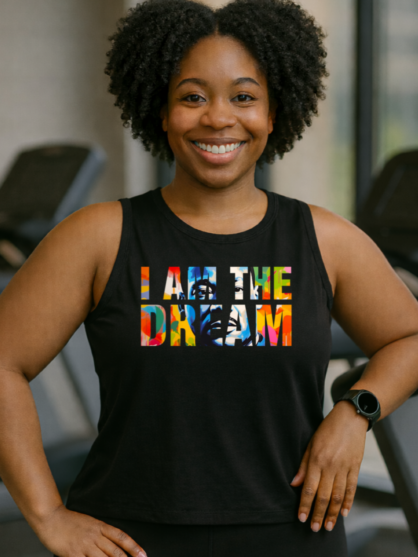 Black girl wearing a black tank top with colorful text i that says I am the Dream n a gym setting