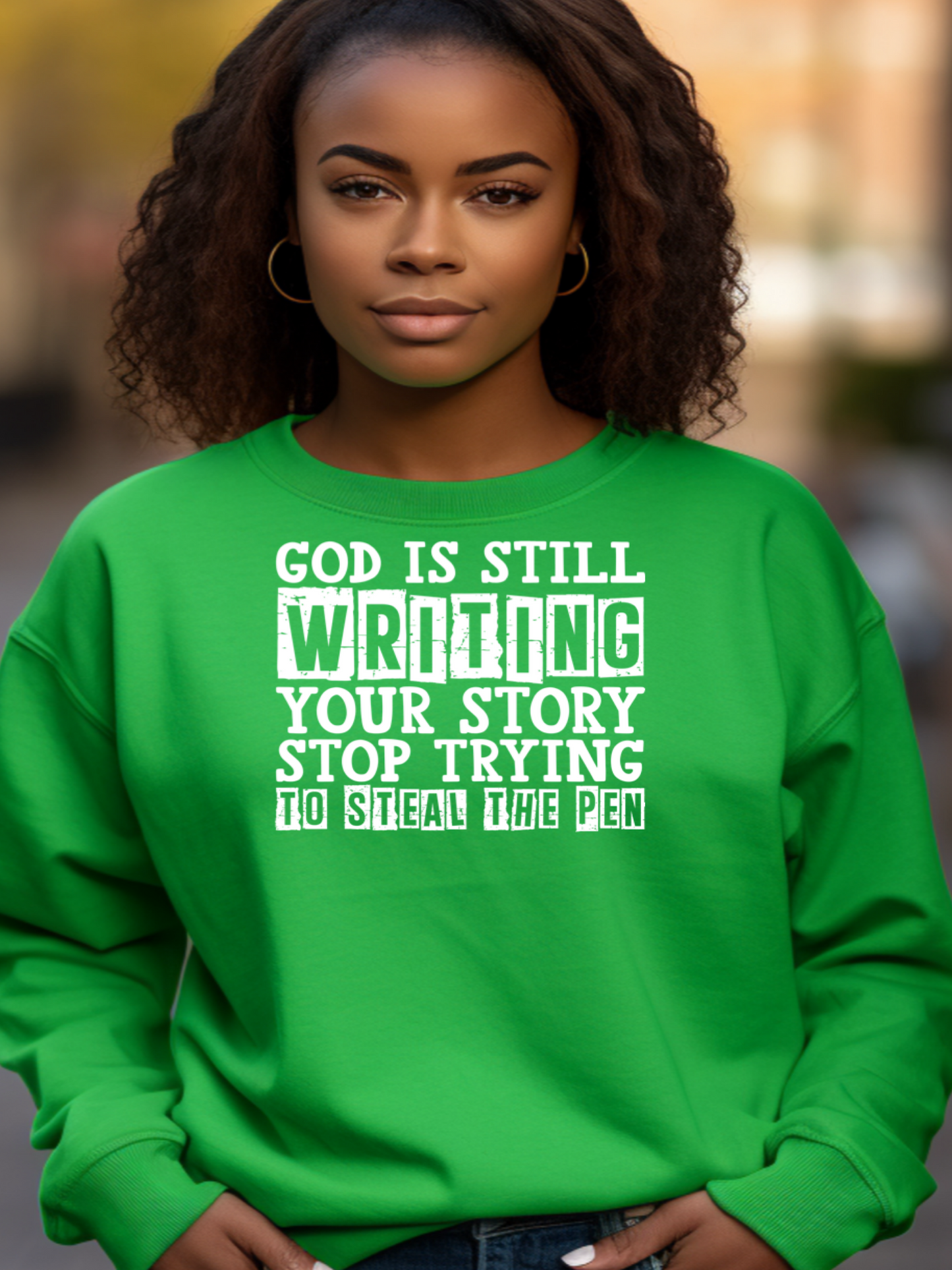 A woman of faith wearing a green sweatshirt that says God is still writing your stroy in an outdoor setting