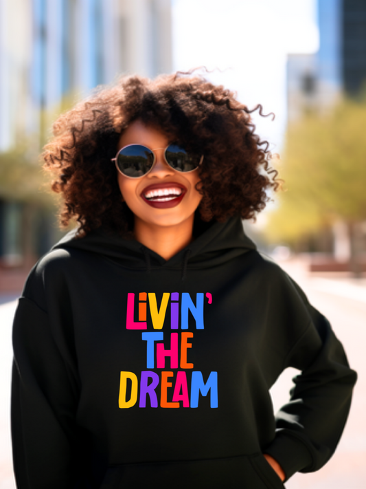 Girlwith curly hair smiling, wearing a black Livin' The Dream hoodie