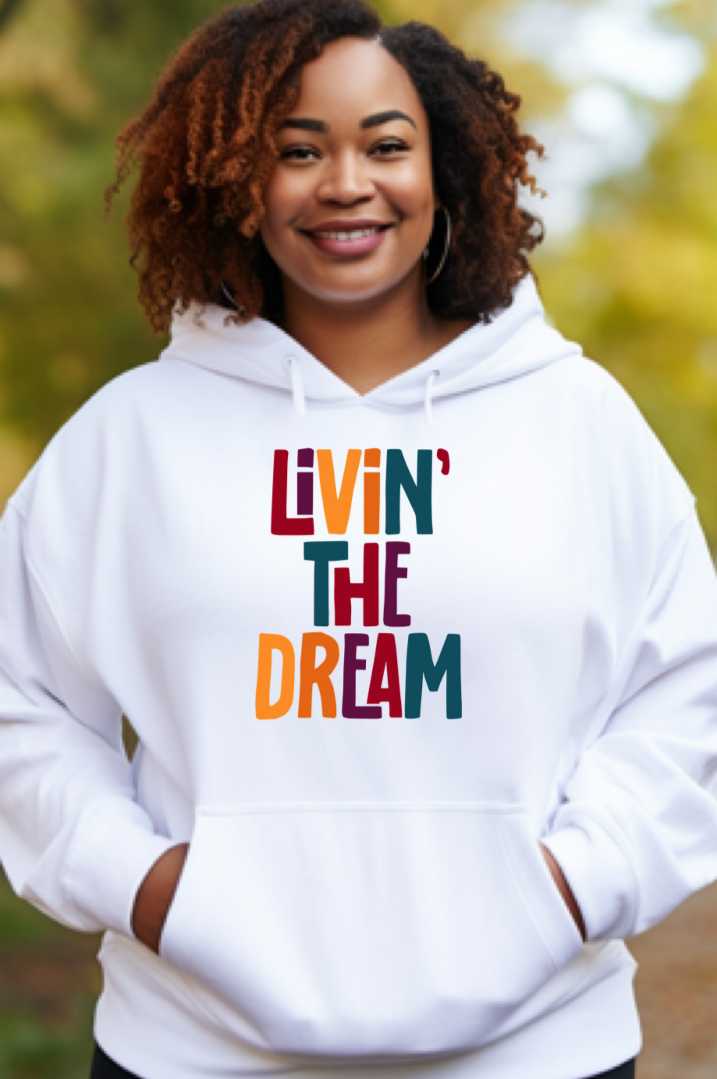 A black Girl with naturally curly hair wearing a white hoodie that says Livn' The Dream