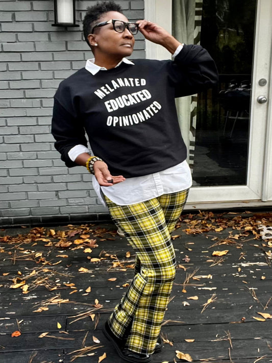 Black girl wearing Melanated Educated Opinionated Black Sweatshirt. stadning outside on a fall day