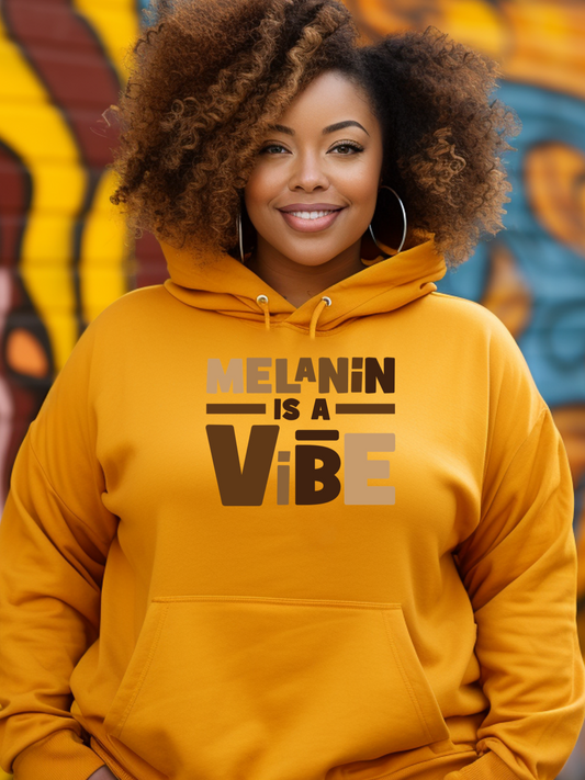 Person wearing a yellow hoodie with 'Melanin is a Vibe' text, standing in front of a colorful mural.