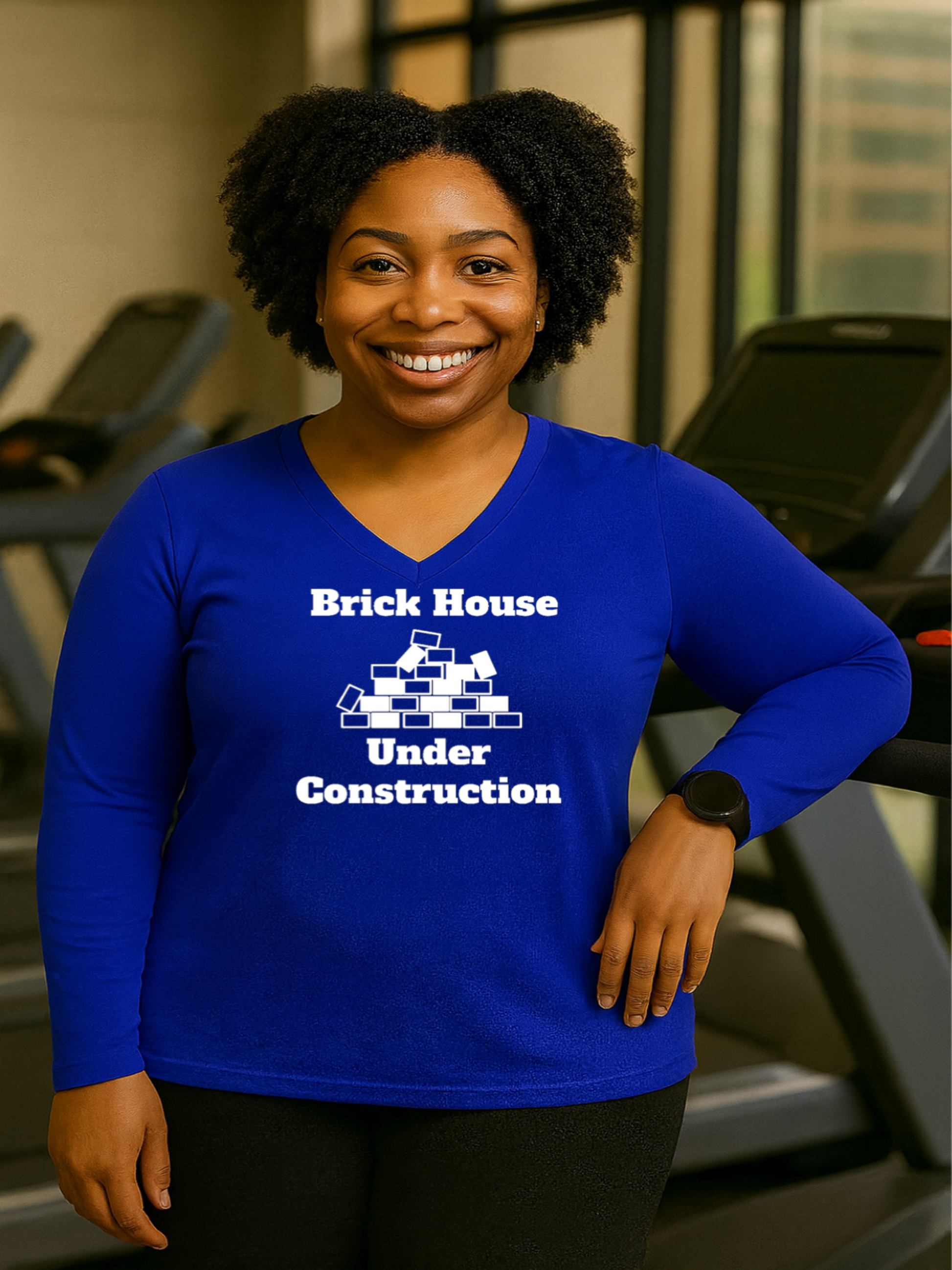 Woman wearing a blue shirt with 'Brick House Under Construction' text in a gym setting