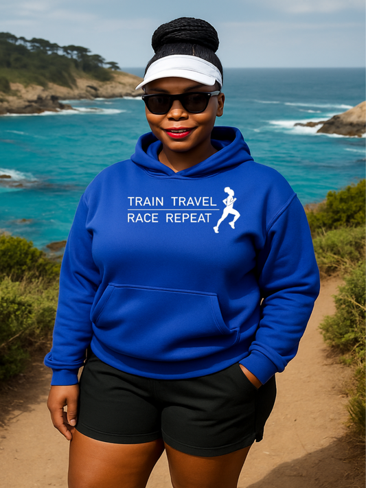 Person wearing a blue hoodie with 'Train Travel Race Repeat' text and a running silhouette, standing on a coastal path.