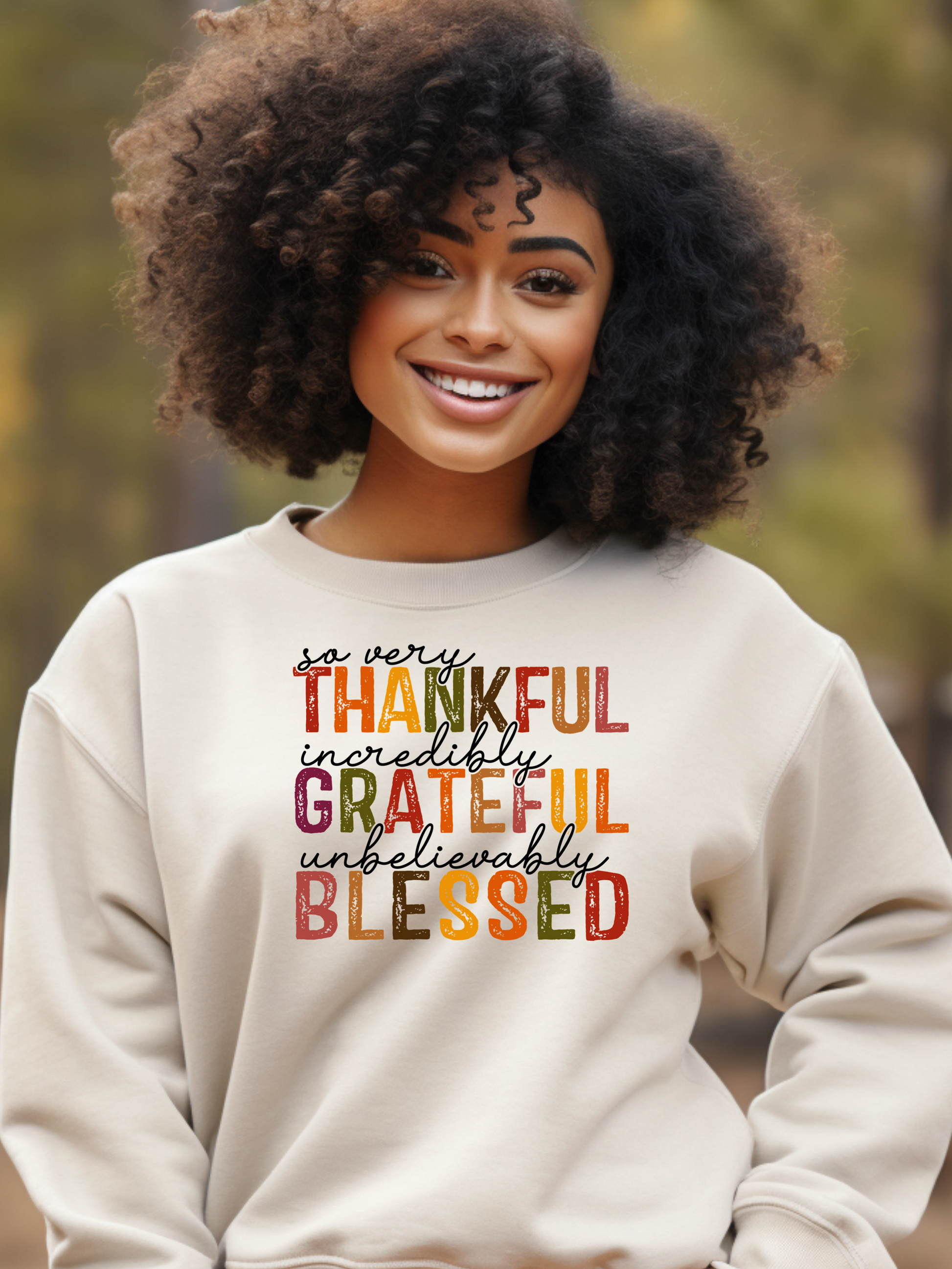 A black girl wearing a tan sweatshirt with the Thankful Grateful Blessed design