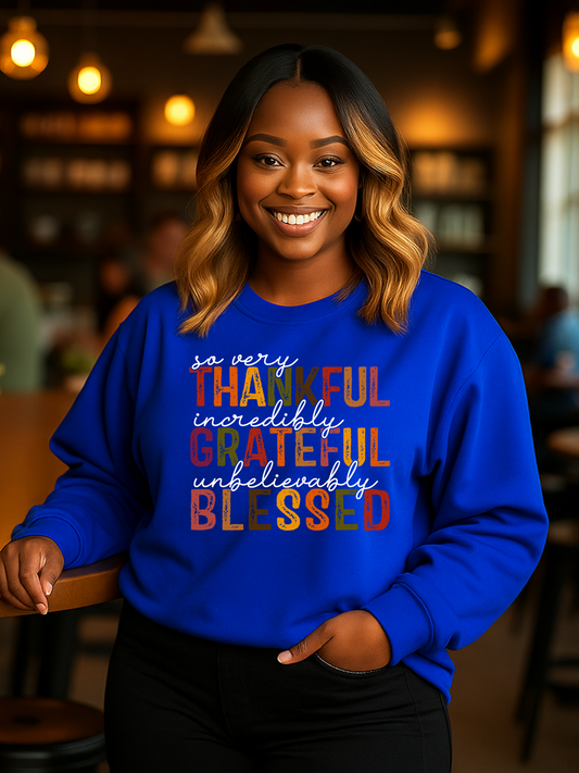 Black Woman wearing a blue sweatshirt with colorful text:  Thankful Grateful Blessed in a casual setting