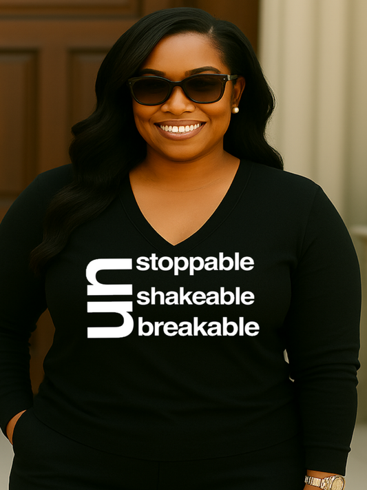 Woman wearing a black shirt with motivational text, smiling outdoors.