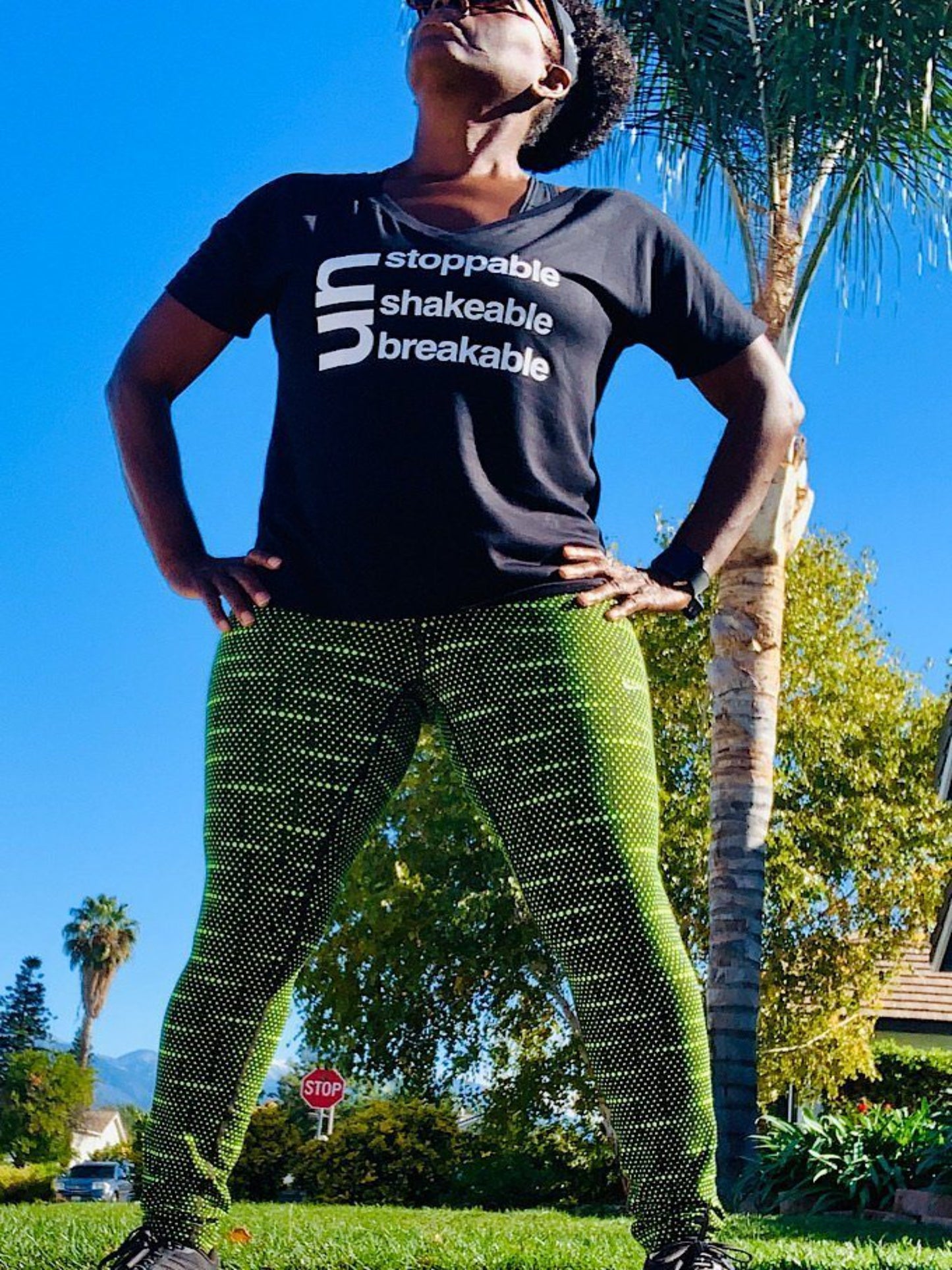 Black girl standing with hands on hip looking up wearing a black unstoppable Unshakeable Unbreakable T-shirt